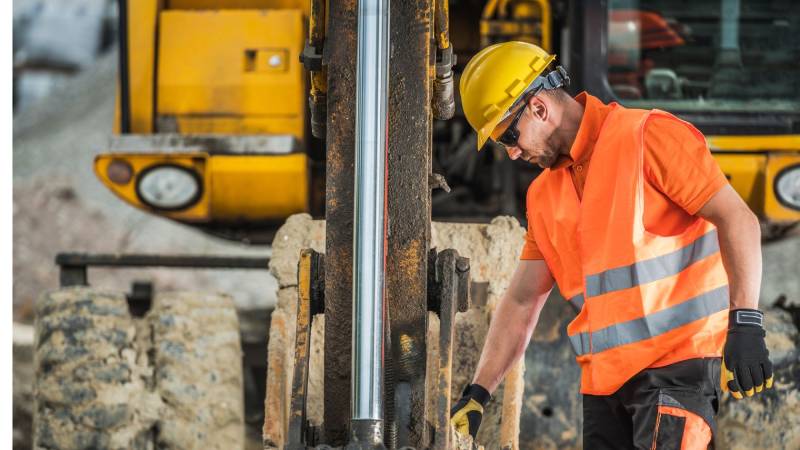 A construction worker in high-visibility clothing inspecting the hydro excavation drilling process, ensuring safety and precision on the job site.